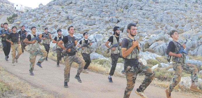 Free Syrian Army fighters, holding their weapons, run during military training north of Idlib on Sunday.