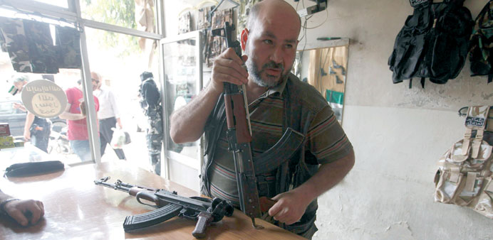 A member of the Free Syrian Army checks a weapon before buying it inside a shop in the Al Myassar neighbourhood of Aleppo yesterday.