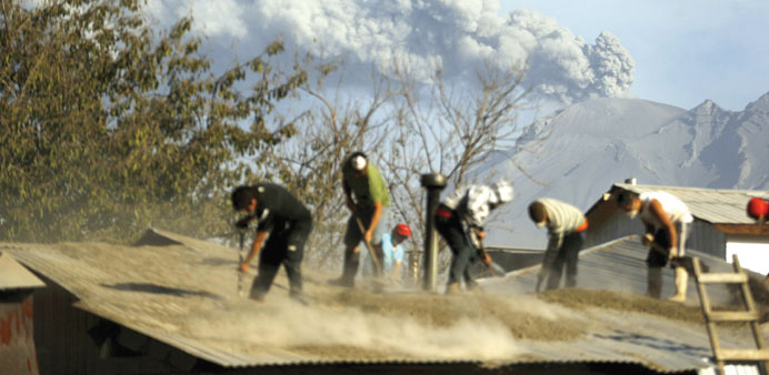 Chileans clean an ash-covered roof of a house in Ensenada town.