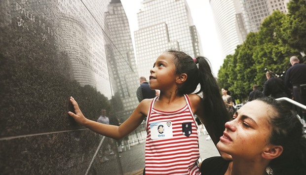 Bernadette Ortiz holds up her daughter Adriana as she looks for the name of her grandfather New York City Police officer Edwin Ortiz at a wall commemorating fallen officers on Friday in New York City.