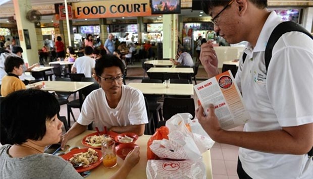 A National Environment Agency officer distributes mosquito repellant to a couple at a food court in Singapore. Singapore's Zika outbreak escalated on Thursday after Malaysia said one of its citizens returned infected from the city-state.