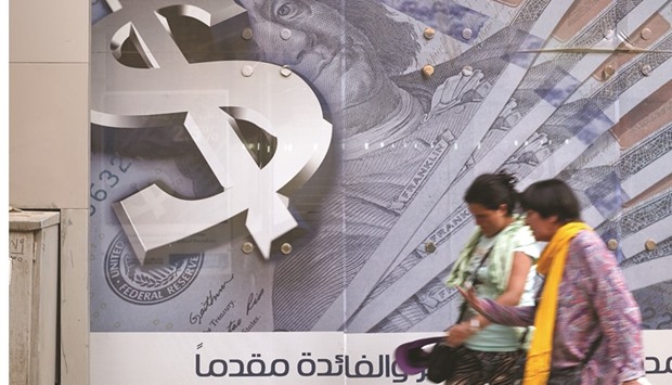 Pedestrians walk past an advertisement displaying a large dollar sign and US dollar banknotes outside a bank in Cairo (file). About 40% of the participant banks in a survey in the Arab region indicated the US as being the home jurisdiction of the largest share of banks that are withdrawing CBRs.