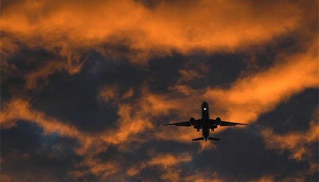 A passenger plane flies towards Heathrow airport at dawn in London on Monday.