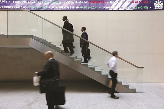 People walk past an electronic information board at the London Stock Exchange in the City of London (file). Shares in London fell yesterday as sterling rallied after figures showed Britainu2019s manufacturing activity hit a 10-month high in August, rebounding strongly from a slump triggered by the countryu2019s vote in favour of exiting the EU.
