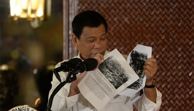 Philippine President Rodrigo Duterte holds up a photo, citing accounts of US troops who have killed Muslims during the US occupation of the Philippines in the early-1900s, during a speech at Malacanang palace in Manila.