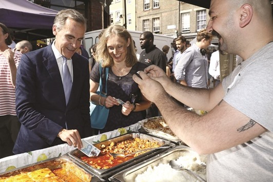 Bank of England governor Mark Carney tests a new polymer u00a35  note as he buys lunch at Whitecross Street Market in London yesterday.Leader of the opposition Labour Party Jeremy Corbyn.