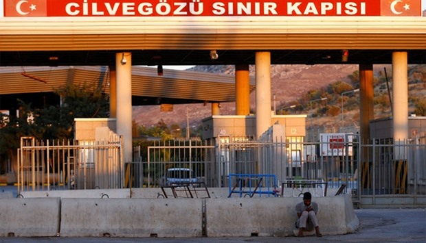 A man sits in front of the Turkish Cilvegozu border gate, located opposite the Syrian commercial crossing point Bab al-Hawa, in Reyhanli, Hatay province, Turkey