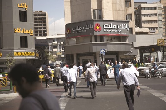 Pedestrians cross a street near a Bank Mellat branch and a Bank Pasargad branch in Tehran. Nearly 180 Iranian individuals and entities are still on the US sanctions list, notably the Revolutionary Guards, the ministries of defence, culture and intelligence, as well as defence companies, two airlines and several banks.