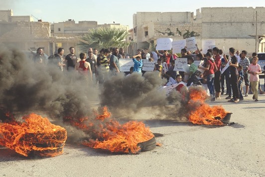 People gather near burning tyres during a demonstration against forces loyal to Syriau2019s president Bashar al-Assad and calling for aid to reach Aleppo near Castello road in Aleppo.