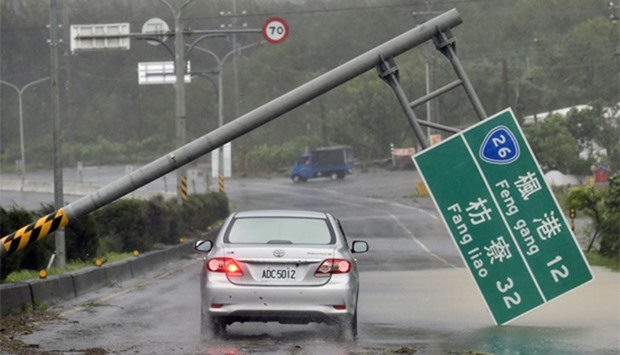 A car drives pass a collapsed traffic sign, toppled by strong winds of typhoon Meranti