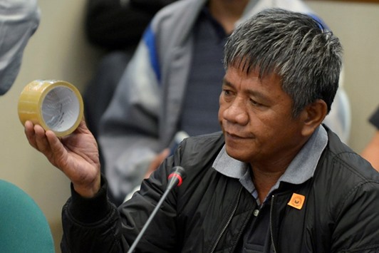 Edgar Matobato, a self-confessed former hitman, holds up a roll of tape, the type of which he claims he used on his victims, during a Senate hearing on drug-related extra-judicial killings, in Pasay city, Metro Manila, yesterday.