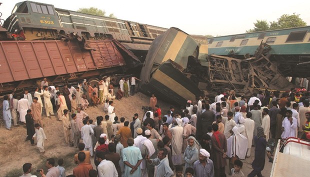 People gather beside the wreckage at the site of the collision on the outskirts of Multan yesterday.