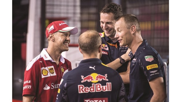 Ferrari driver Sebastian Vettel (left) talks to Red Bull team members in the paddock ahead of Sundayu2019s Singapore Grand Prix yesterday. (AFP)