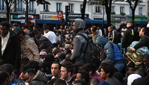 Migrants gather and wait before being evacuated from a makeshift migrant camp set up between the metro stations of Jaures and Stalingrad, in Paris.