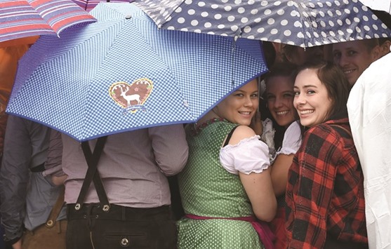Visitors wait for the opening of a festival tent at the Oktoberfest beer festival during heavy rain in Munich.