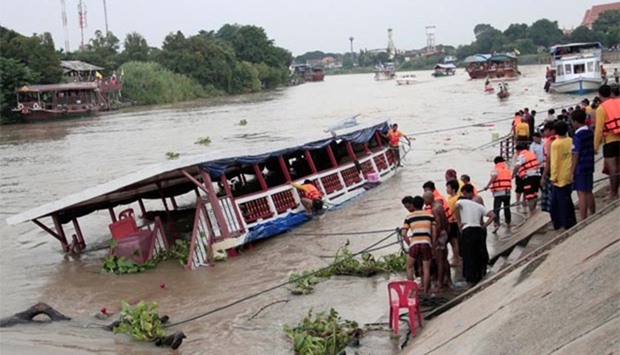 People stand near a boat which officials said capsized on the Chao Phraya river, in the ancient tourist city of Ayutthaya on Sunday.