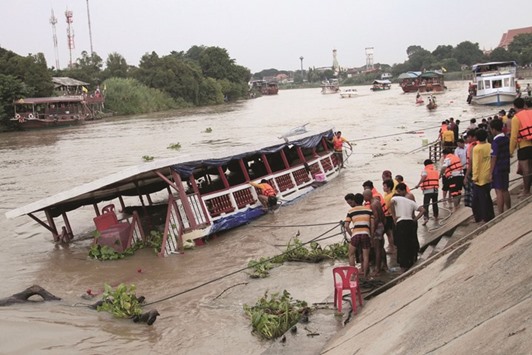 People stand near a boat which according to officials, capsized on the Chao Phraya river while carrying pilgrims, in the ancient tourist city of Ayutthaya yesterday.