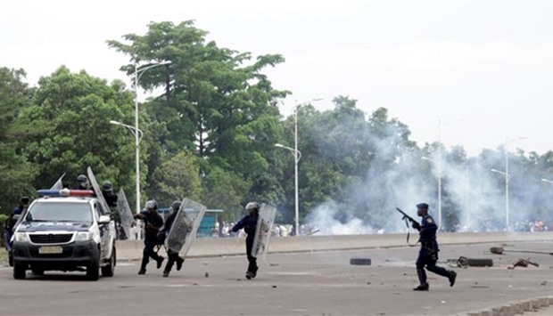 Congolese policemen run to their vehicle during a clash with opposition activists in Kinshasa on Monday.