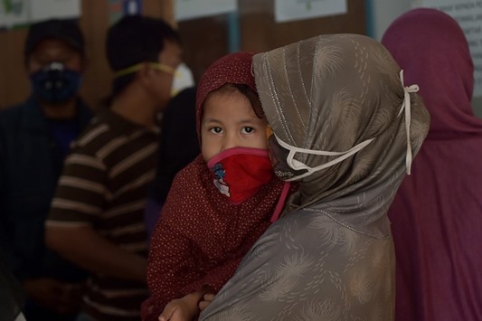 File photo shows an Indonesian mother holding her daughter as they wait at a health centre following thick haze in Pekanbaru in Riau province.