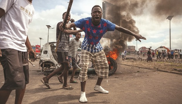  Protesters demonstrate in front of a burning car during an opposition rally in Kinshasa yesterday.