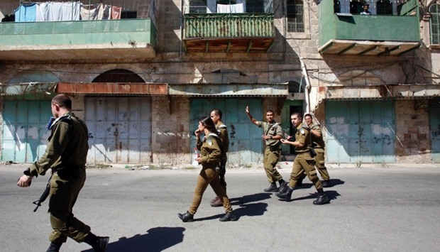 Israeli soldiers patrol the West Bank city of Hebron yesterday, as Israeli security forces closed off access near the Jewish settlers zones in the neighbourhoods of Tel Romeida, Beit Hadassa and Abraham Avino after a series of attacks by Palestinian assailants.