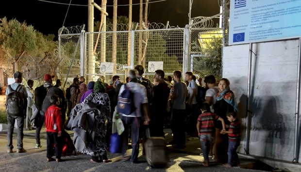 Refugees and migrants stand at the closed gate of the Moria migrant camp, after a fire at the facility, on the island of Lesbos, Greece, yesterday.