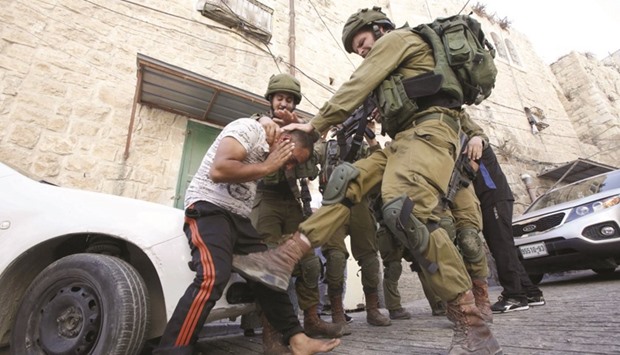 An Israeli soldier kicking a Palestinian man as troops try to arrest him in the flashpoint city of Hebron, in the Israeli occupied West Bank, on Tuesday. The man was named by family members, who witnessed his arrest, as Mohamed al-Kawasmi, 30, whom they said suffers from psychological troubles.