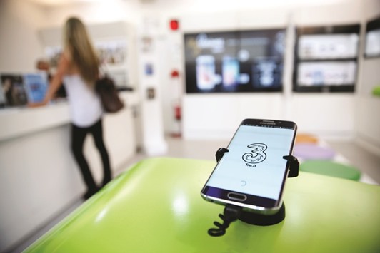A logo is displayed on a mobile phone screen inside a 3 Italia store, operated by CK Hutchison Holdings, in Rome. Hutchison and VimpelCom got green light for a merger only after delivering u201ca remedyu201d to the EUu2019s concerns about reduced rivalry, Competition Commissioner Margrethe Vestager said.