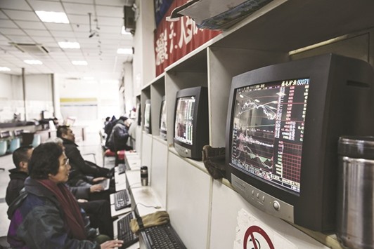 People sit at trading terminals at a securities exchange house in Shanghai. The Shanghai Composite Index added 0.1% yesterday.