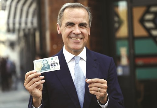 Bank of England governor Mark Carney poses with a new polymer five pound note in London. The BoEu2019s Financial Policy Committee said yesterday that banks shouldnu2019t increase dividends as a result of the countercyclical capital buffer rate being held at zero per cent for UK exposures.