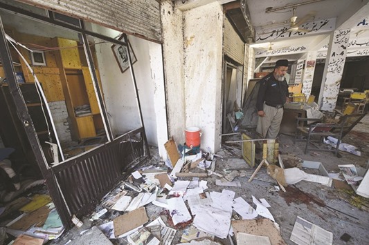 A police officer inspects the site of a suicide bomb attack at a district court in Mardan yesterday.