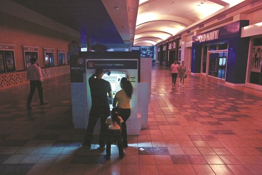 People use an ATM machine at a shopping mall in San Juan during the power  outage that affected several areas in the Puerto Rico.