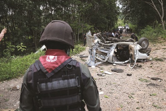 Thai police and army personnel inspect the scene of a bomb attack which left three police officers dead in Thailandu2019s restive southern province of Yala.