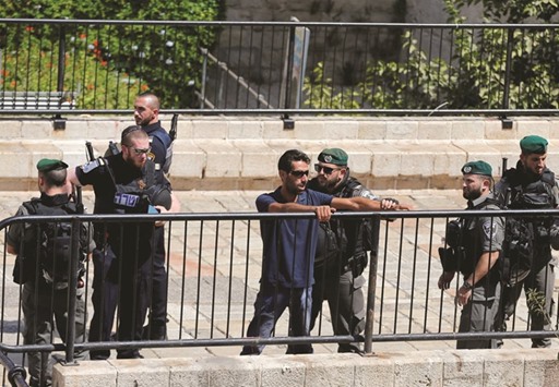 An Israeli border policeman performs a body search on a Palestinian man near Damascus Gate in Jerusalemu2019s Old City yesterday.
