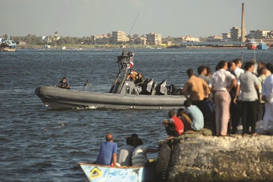 Egyptian rescue workers arrive on a boat carrying bodies of migrants, during a search operation after a boat carrying migrants capsized in the Mediterranean, along the shore in the Egyptian port city of Rosetta.