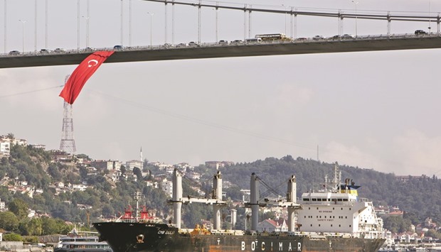 A bulk carrier sails beneath a Turkish national flag hanging from July 15th Martyrs bridge on the Bosporus strait, in Istanbul on August 29, 2016. With the rating cut, the difficulties Turkey faces in attracting the foreign capital needed to cover its current-account deficit, the fourth largest in the G20 group of major economies, are likely to be compounded.