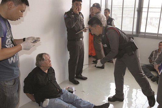 A foreign member of a suspected passport forgery gang (second left) is detained by police officers after a raid in Bangkok yesterday.