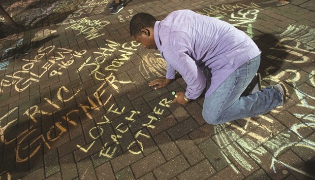 A man writes on the sidewalk tribute in Charlotte during a demonstration on Friday night.