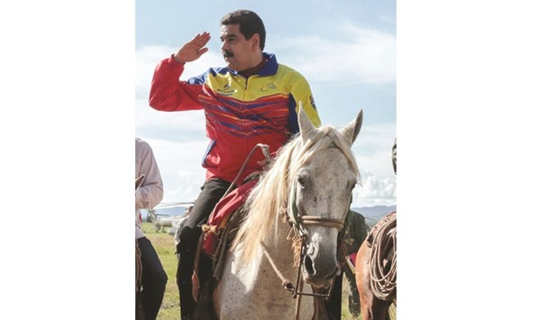 President Nicolas Maduro salutes while riding a horse during a visit to a farm in Cojedes state, Venezuela.