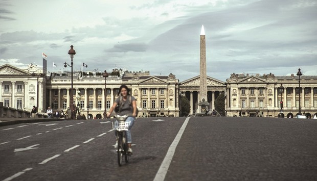 A woman rides a bicycle along a street emptied of cars in Paris yesterday.