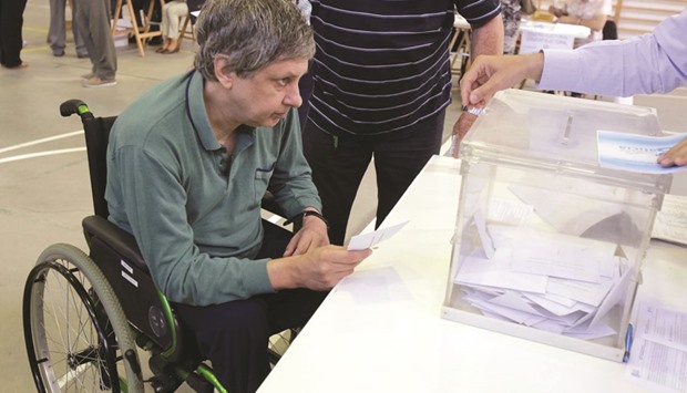 A man in a wheelchair casts his vote during the regional parliamentary elections at a polling station in Vigo, northern Spain.