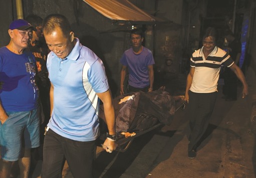 Workers carry the dead body of an alleged drug pusher in Manila.