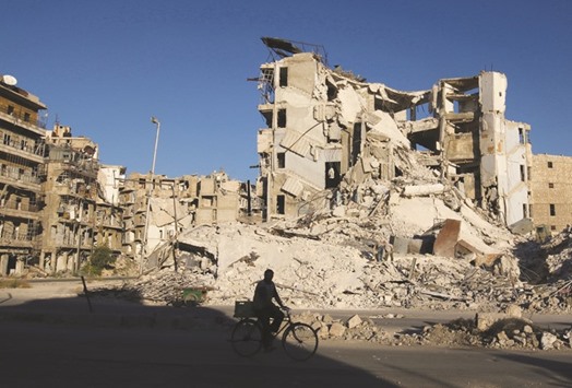 A man rides a bicycle past damaged buildings in the rebel-held Tariq al-Bab neighbourhood of Aleppo.