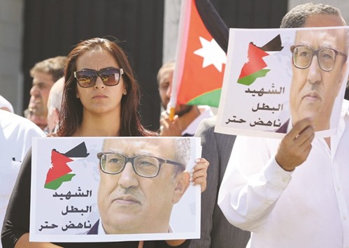 Protesters hold portraits of Jordanian writer Nahed Hattar during a demonstration in Amman yesterday.