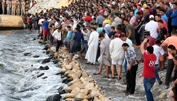 Egyptians stand on the shore as they wait for the recovery of bodies, during a search operation after a boat carrying migrants capsized in the Mediterranean, along the shore in the Egyptian port city of Rosetta on September 22, 2016