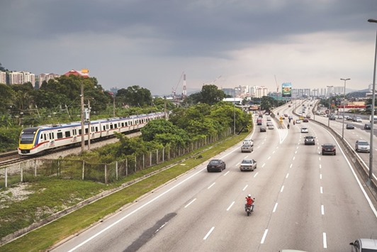 A Malayan Railways train travels along railway tracks as vehicles drive along a highway in Petaling Jaya, Selangor, Malaysia (file). Top underwriters see Malaysian corporate sukuk sales rebounding from a four-year low as Prime Minister Najib Razak ramps up spending to boost an economy forecast to grow at the slowest pace since 2009.