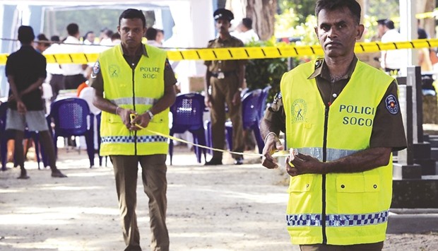 Police officials standing near the grave of anti-establishment newspaper editor Lasantha Wickrematunga as his body was exhumed at a cemetery in Colombo yesterday.
