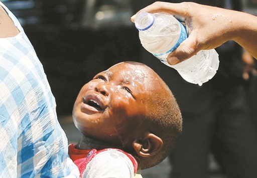 A woman pours water over a child affected by teargas after clashes between police and street vendors in central Harare yesterday.