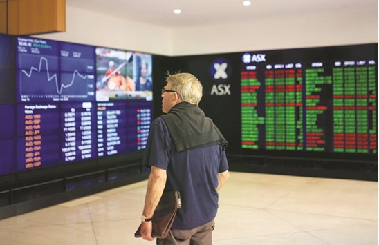 An investor looks at boards displaying stock prices at the Australian Securities Exchange in Sydney. The ASX closed slightly higher yesterday.