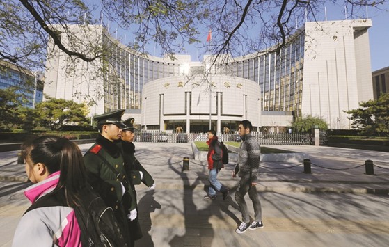 People walk past the headquarters of the Peopleu2019s Bank of China as two paramilitary police officials patrol around it in Beijing. The Chinese central bank will continue using longer-term tenors in its open-market operations to drive up borrowing costs, said all but one of the surveyu2019s 17 respondents, while a majority suggested a record rally in sovereign bonds will cool.